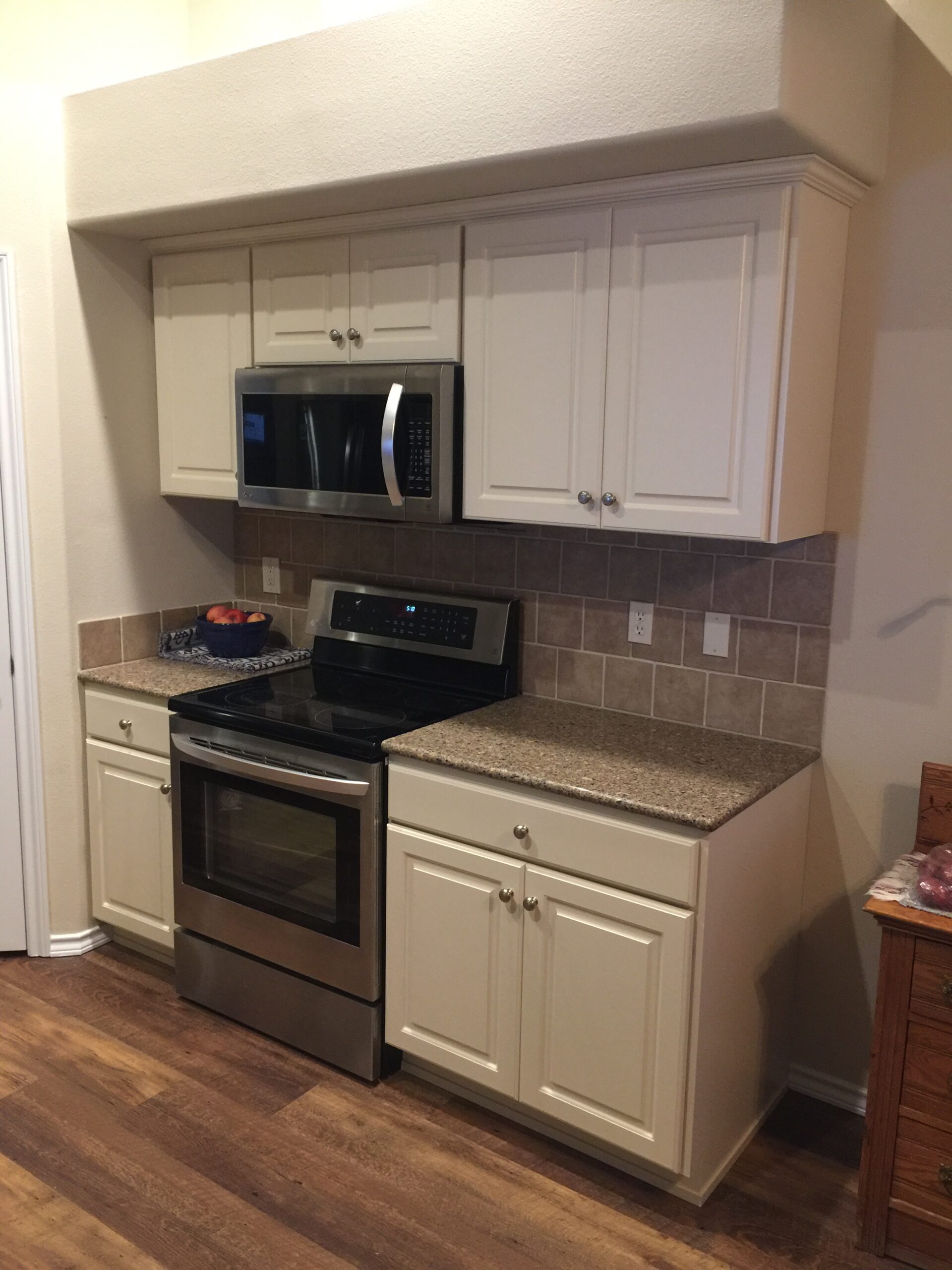 Modern Kitchen Showcasing Stainless Steel Appliances, Beige Cabinets, and a Spacious Layout With Hardwood Floors, Ideal for Cooking and Entertaining.